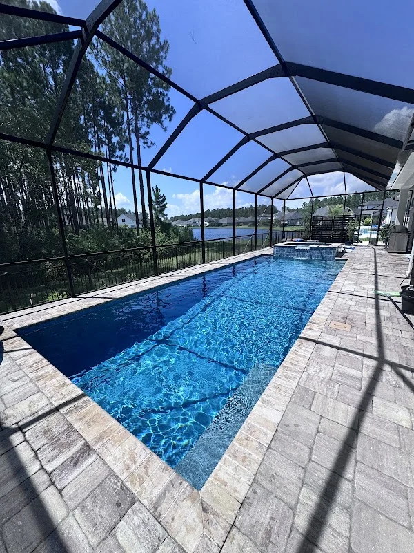 Long rectangular pool with a spa inside a screened enclosure
