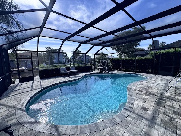 Curved backyard pool inside a screened patio